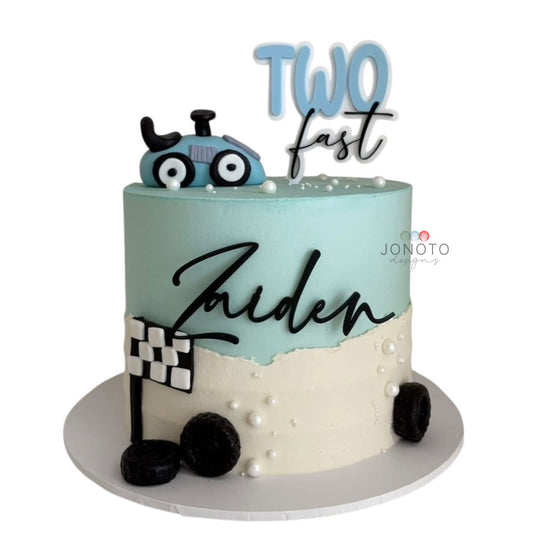Two-layer cake with blue and white frosting, toy car, and 'Zaiden' written on it, with a white background.